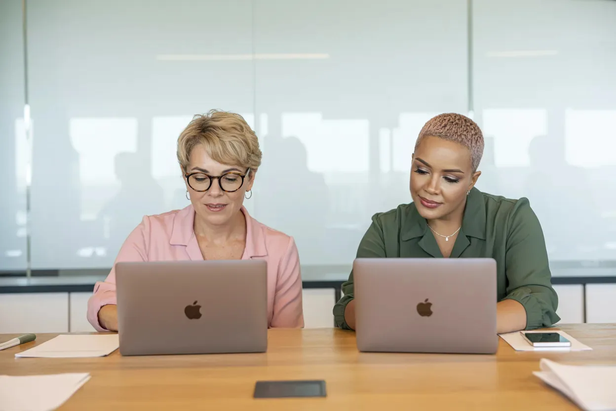 Two professionals working side by side at their laptops
